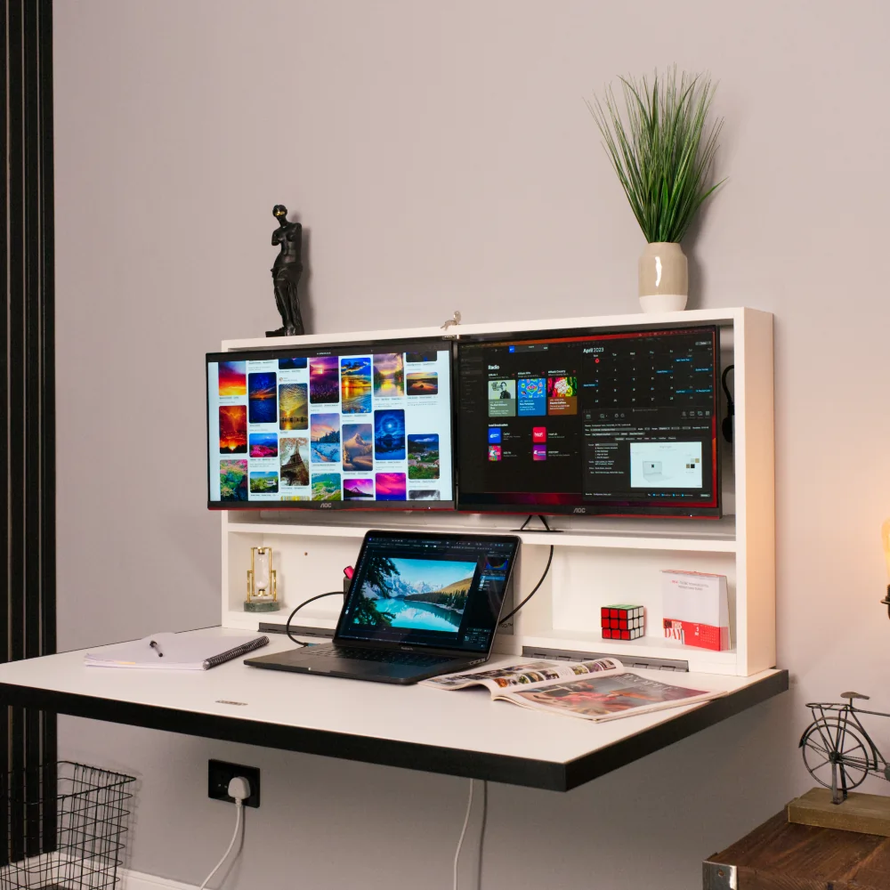 Wall-mounted fold-down Murphy desk with integrated dual monitors, a laptop, and workspace. The hideaway desk setup features sleek storage with decor, offering a compact and functional work-from-home solution.