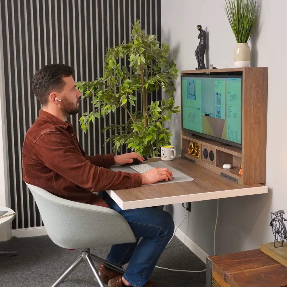 Man sat at fold down desk in a home enviroment.